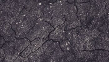 Close-up of cracked earth with dark tones, showcasing natural textures and patterns.