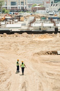 Overhead drone shot of a construction site with two workers in safety gear.